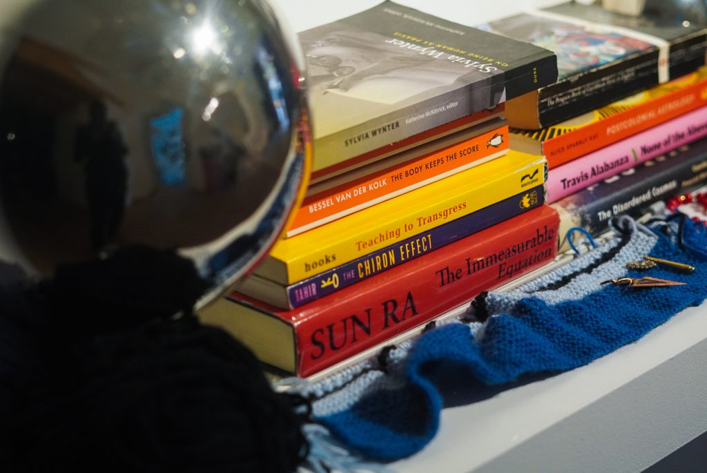 a detailed shot of one of HCJ's altar shelves from the exhibtion showing a pile of books and a mirror ball.