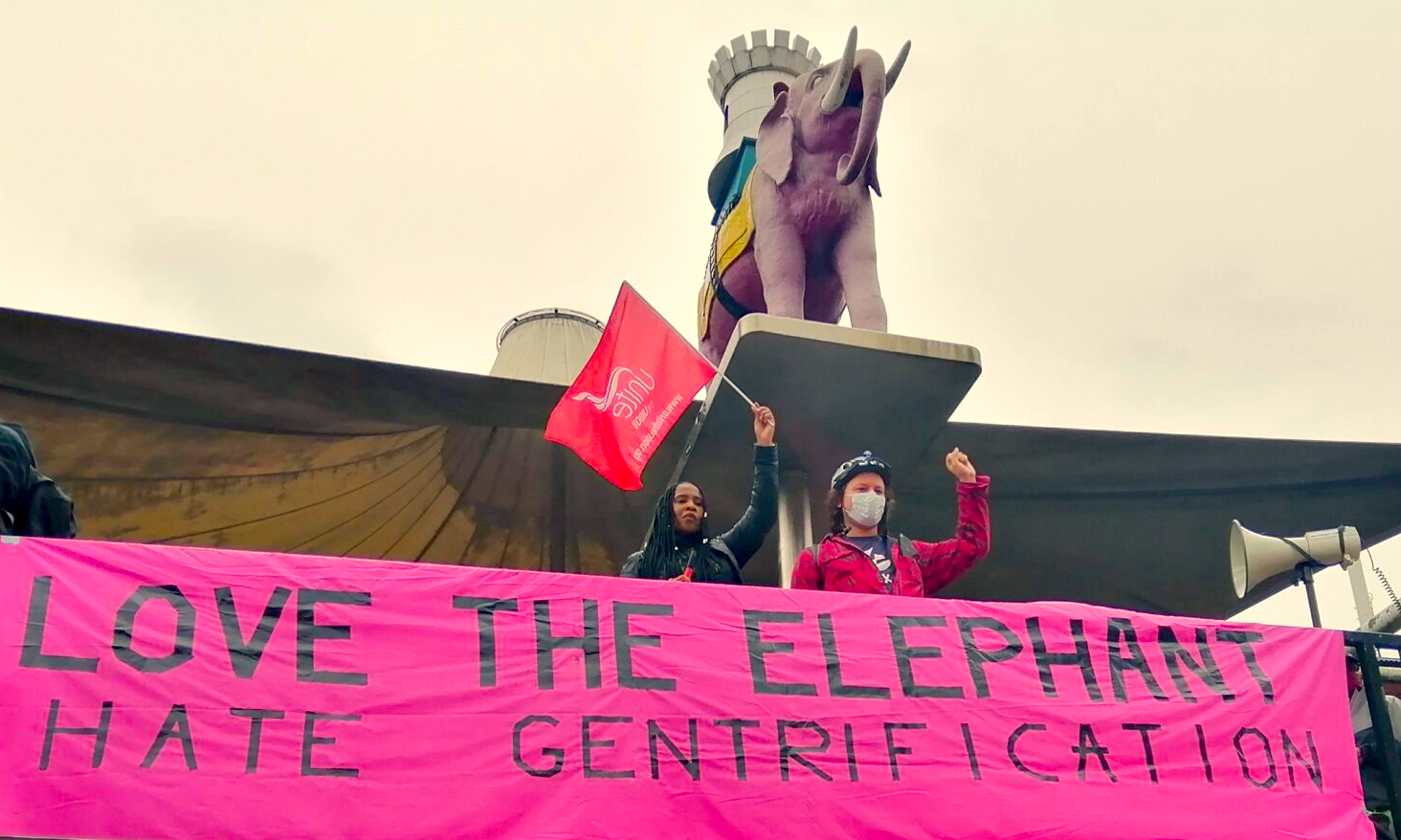 Documentation from Up the Elephant Demo showing two people beneath the pink Elephant. The pink banner below them reads 'Love the Elephant Hate Gentrification'