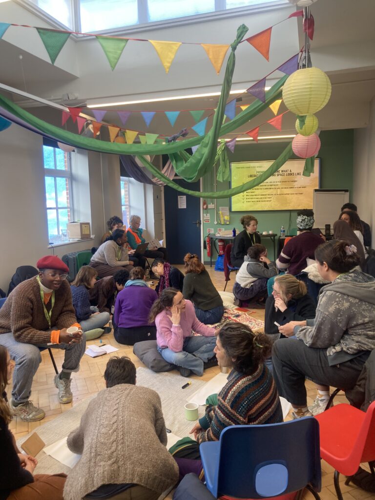 people sitting in groups on the floor and on chairs discussing 